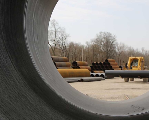 tractor carrying pipe through yard