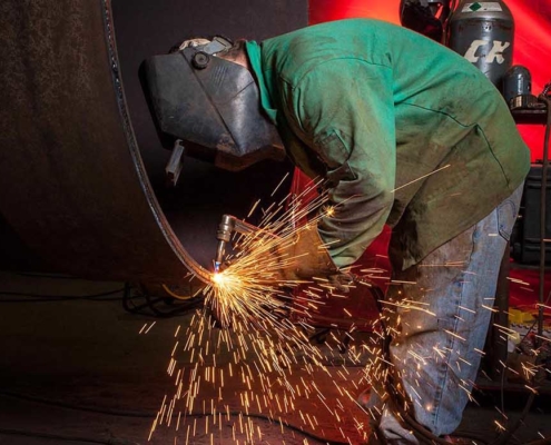 worker using cutting welder on large pipe