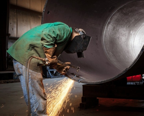Worker using welding tool on large diameter pipe