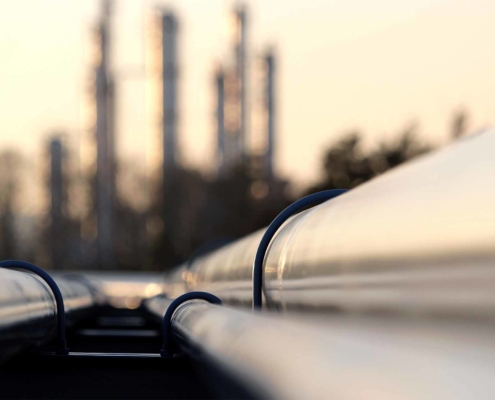 Close up of refinery pipe with oil refinery in the background